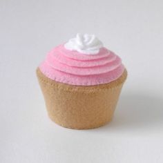 a cupcake with pink icing and white frosting sitting on top of a table