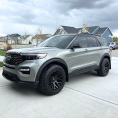 a silver ford explorer is parked in front of some houses