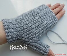 a woman's hand is wearing a gray knitted mitt with white thread