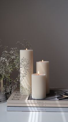 three white candles sitting on top of a book