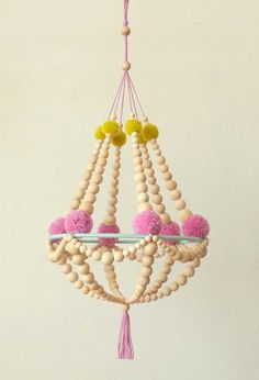 a chandelier made out of wood beads and pink pom - poms