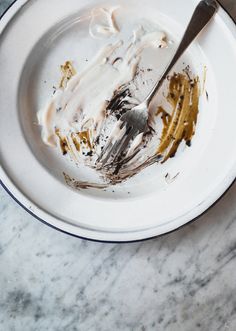 a white plate topped with cake next to a knife and fork on top of a marble table