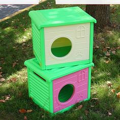 two green and pink boxes sitting in the grass next to a tree with leaves on it