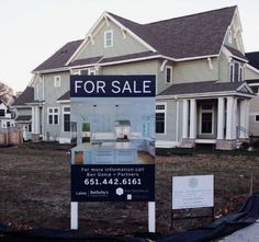 a for sale sign sitting in front of a large house with lots of yard space