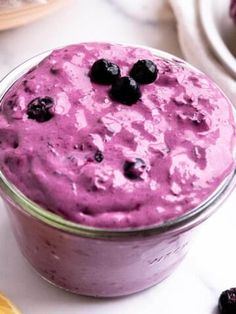 a close up of a bowl of food with blueberries on the top and lemons in the background