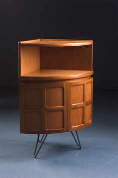 a wooden cabinet sitting on top of a blue floor next to a black wall with an open door