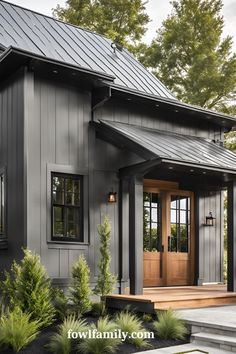 a gray house with black shingles and wooden steps leading up to the front door