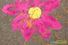 a pink flower is drawn on the ground with colored chalk and crayons in front of it