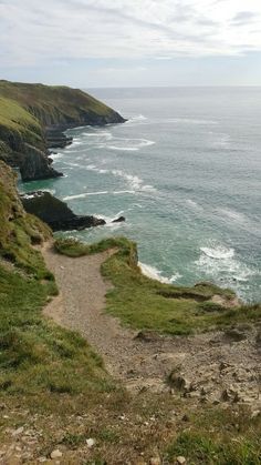 a path leading down to the ocean with cliffs in the background