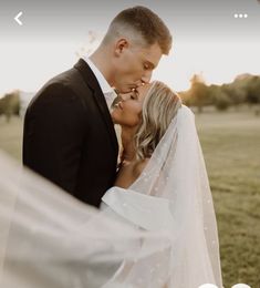 a bride and groom kissing in front of the camera on their wedding day at sunset