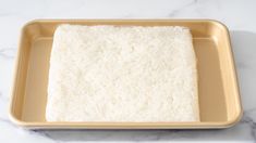 a square cake pan filled with rice on top of a marble counter