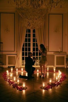 a man kneeling down next to a woman in front of a circle of lit candles