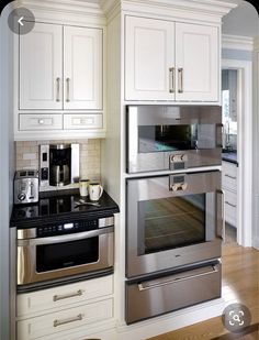 a kitchen with white cabinets and stainless steel ovens in the center, along with wooden flooring