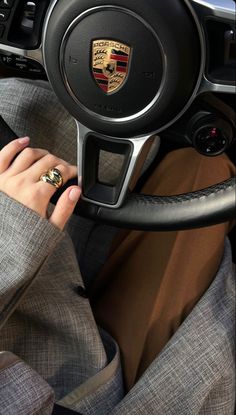 a woman is sitting in the driver's seat of a car with her hand on the steering wheel