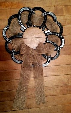 a wreath made out of old horseshoes and burlocks on a wooden floor