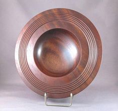 a wooden bowl on a metal stand against a white background with the bottom section showing