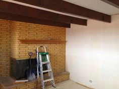 an empty room with a brick fireplace and ladder