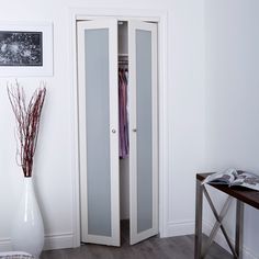 a white room with an open door and a vase on the floor next to it