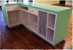 an empty kitchen with green counter tops and white cupboards on the side, in front of a hardwood floor