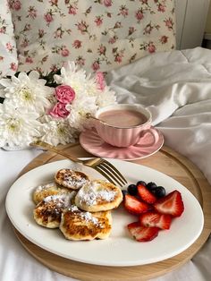 a white plate topped with pastries and strawberries next to a cup of coffee