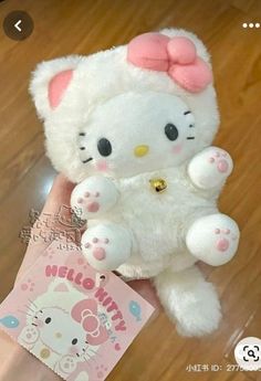 a white hello kitty stuffed animal with a pink bow on it's head and paws