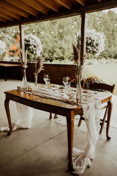 the table is set up for an outdoor wedding reception with flowers in vases on it