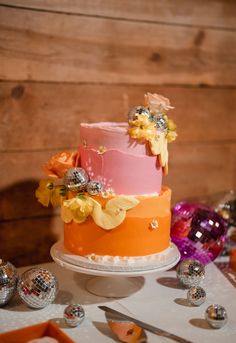 a multi layer cake sitting on top of a table next to silver and orange decorations