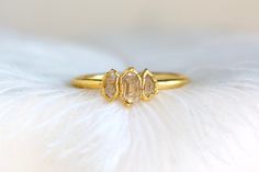 a close up of a ring on top of a white furnishing with feathers in the background