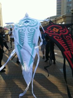 some people are walking down the street with kites in their hands and one has a skeleton on it