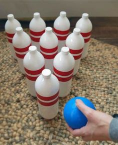 a person holding a blue ball in front of several white jugs on a rug