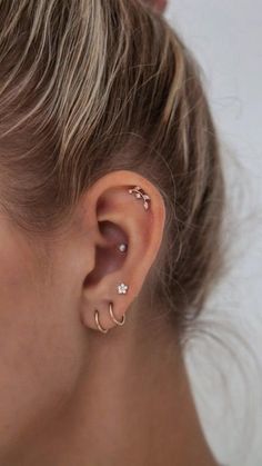 a close up of a woman's ear with two piercings on it and one behind her ear