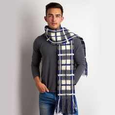 a man standing in front of a white wall wearing a blue and grey plaid scarf