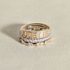 two gold rings with diamonds on them sitting on top of a beige cloth covered surface