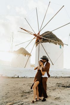 two people standing next to each other near a windmill