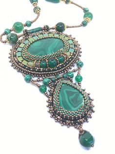 This embroidery necklace is made of Natural Malachite, embellished with green onyx, green agate, aventurine, malachite and tila beads.  The embroidery is done with the finest Japanese seed beads, Miyuki delicas and rounds of different sizes from Miyuki and Toho.       The pendant is a little over 4.5" long and about 2.7" wide.  The "chain" is made of the Japanese seed beads, green onyx, green agate, jasper, ruby zoisite and malachite beads. It measures a little under 19" and has a decorative lobster clasp. The pendant is NOT removable and is intended to be worn as presented.  The design is backed by natural leather for durability. Luxury Traditional Beaded Pendant Necklace, Luxury Formal Beaded Pendant Necklace, Luxury Green Beaded Statement Necklace, Beaded Collar Necklace Patterns, Far Rockaway, Embroidery Necklace, Tila Beads, Beaded Collar Necklace, Beading Inspiration