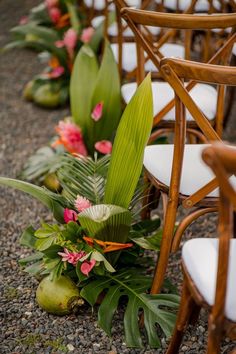 chairs lined up with flowers and greenery on the ground in front of them,