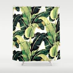 a shower curtain with green and yellow banana leaves on the outside, in front of a white background