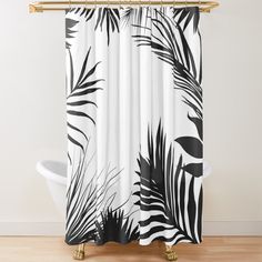 a black and white shower curtain with palm leaves on the outside, in front of a wooden floor