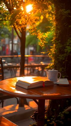 an open book sitting on top of a wooden table next to a cup of coffee