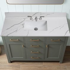 a white sink sitting on top of a bathroom vanity next to a mirror and wooden floor