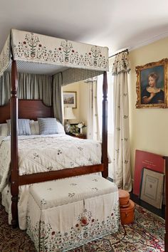 a four poster bed with floral bedspread and pillows