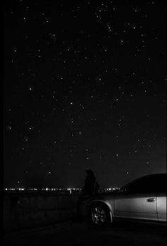 a car parked on the side of a road at night with stars in the sky