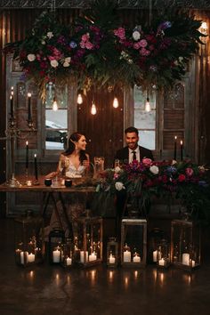 a man and woman sitting at a table with candles