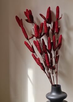 a black vase with red flowers in it