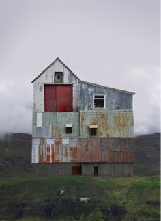 an old barn sits on the side of a hill