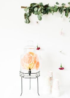 there is a glass jar with oranges in it and some flowers on the wall