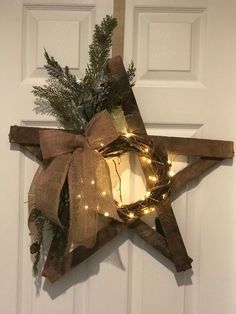 a wooden star decorated with lights and greenery on the front door to give it a festive feel