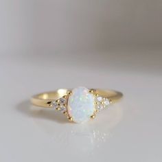 an opal and diamond ring on a white surface