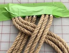 some rope is laying on the ground next to a piece of green paper that has been cut in half