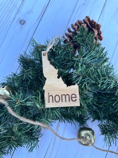 a wooden ornament with the word home hanging from it's side on a christmas tree